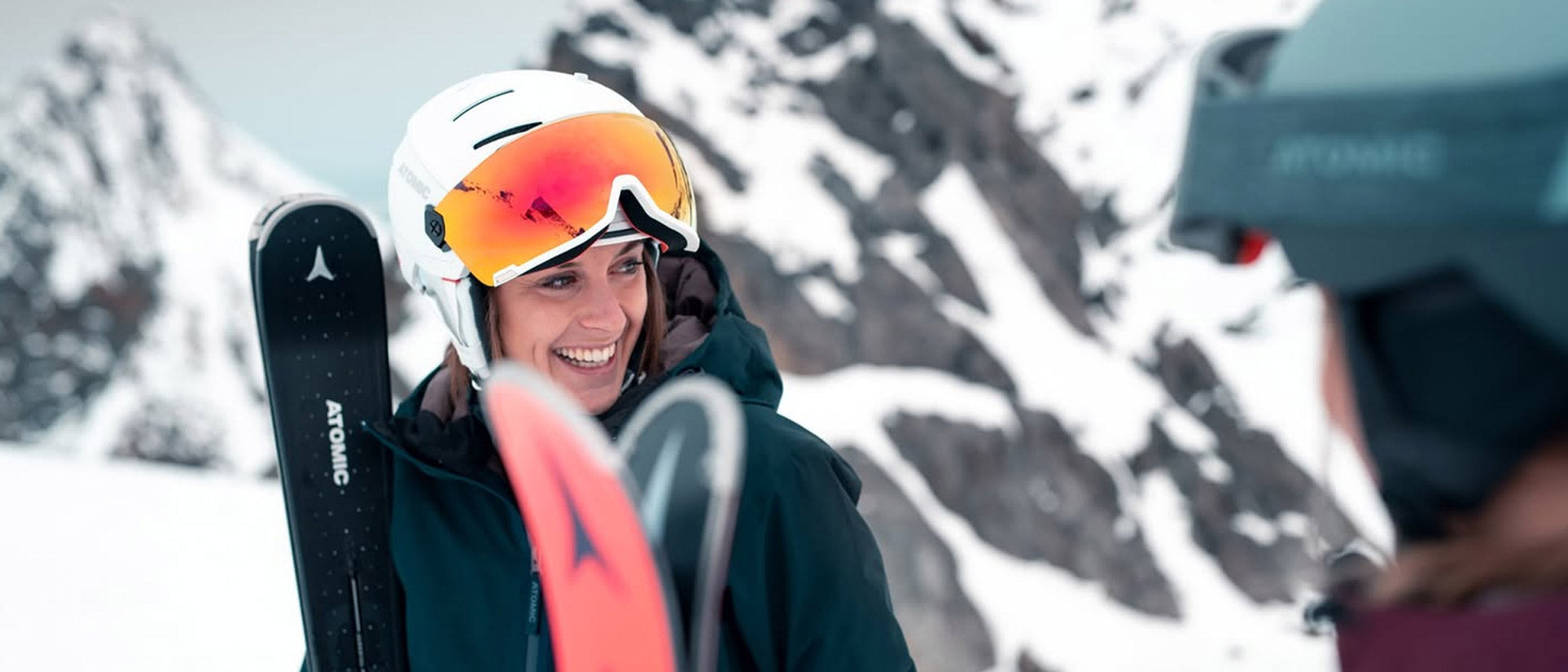 Person with ski equipment and Atomic visor ski helmet in a snowy mountain setting