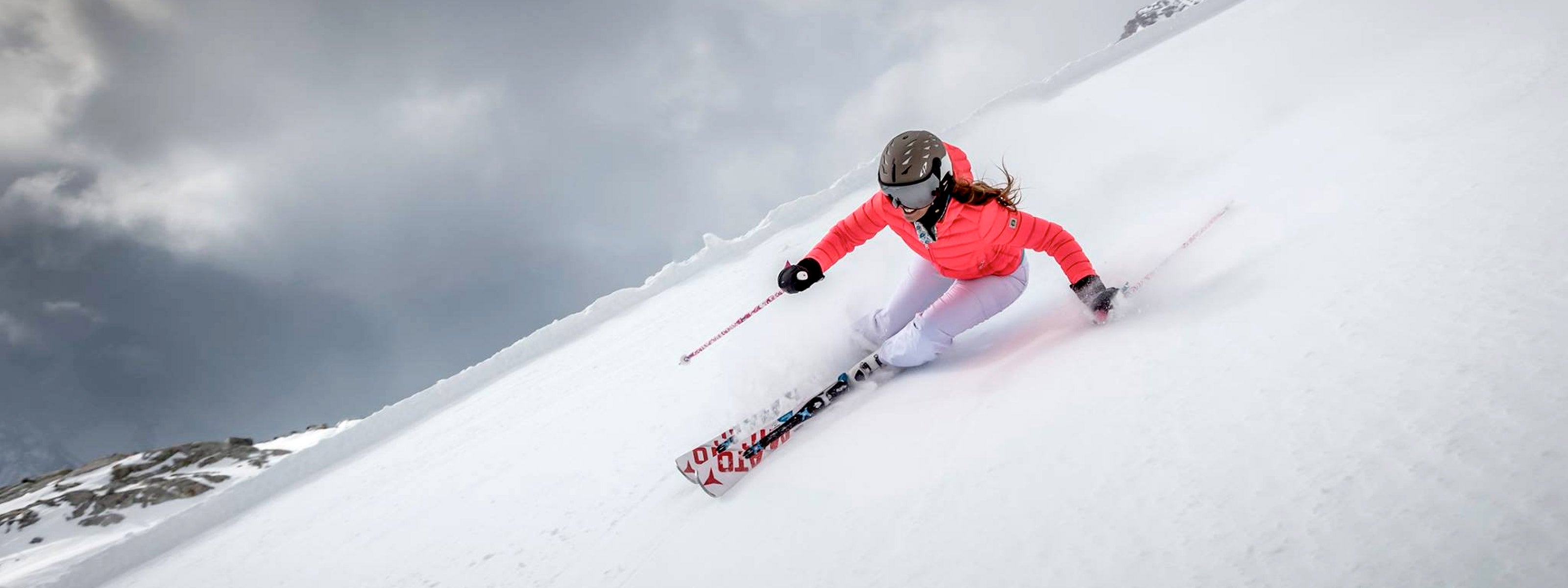 Woman in a pink ski coat skiing in a grey CP Cuma visor ski helmet