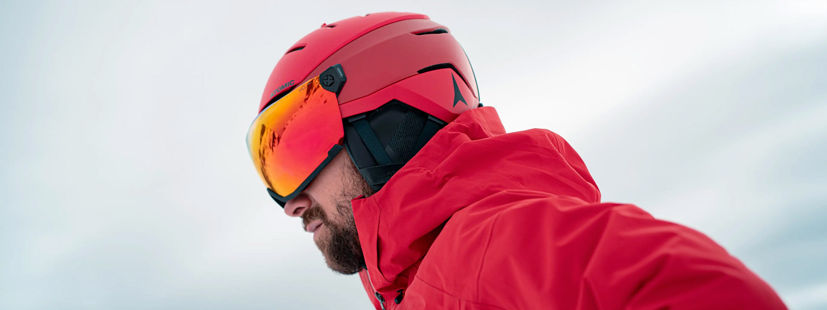 Man wearing a red Atomic visor ski helmet and red ski coat