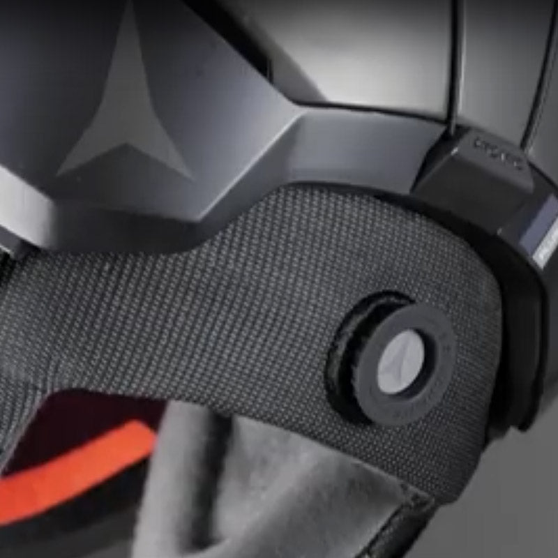 Close-up of a black helmet size dial with a textured chin strap and visible Atomic brand logo.