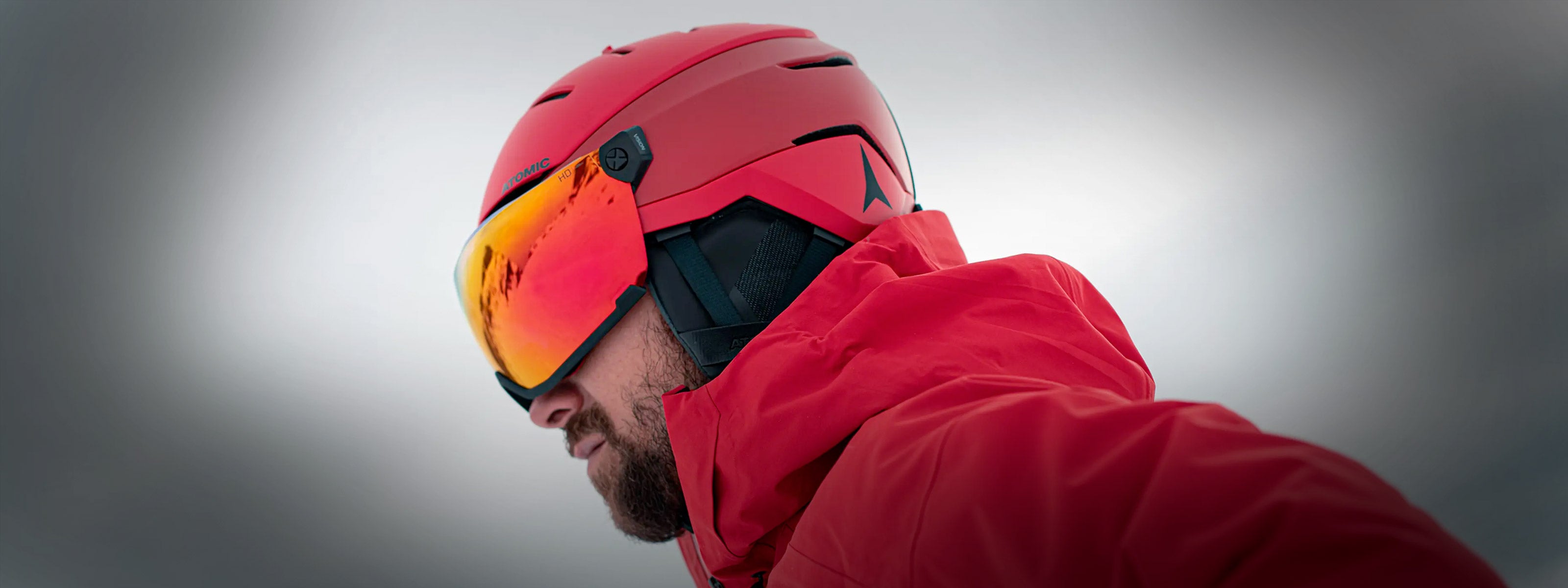 Man wearing an Atomic Visor Ski Helmet and red ski jacket