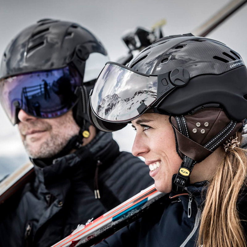 Two skiers wearing visor ski helmets on a mountain background