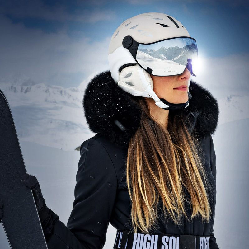Woman in black ski jacket wearing white Cuma visor ski helmet