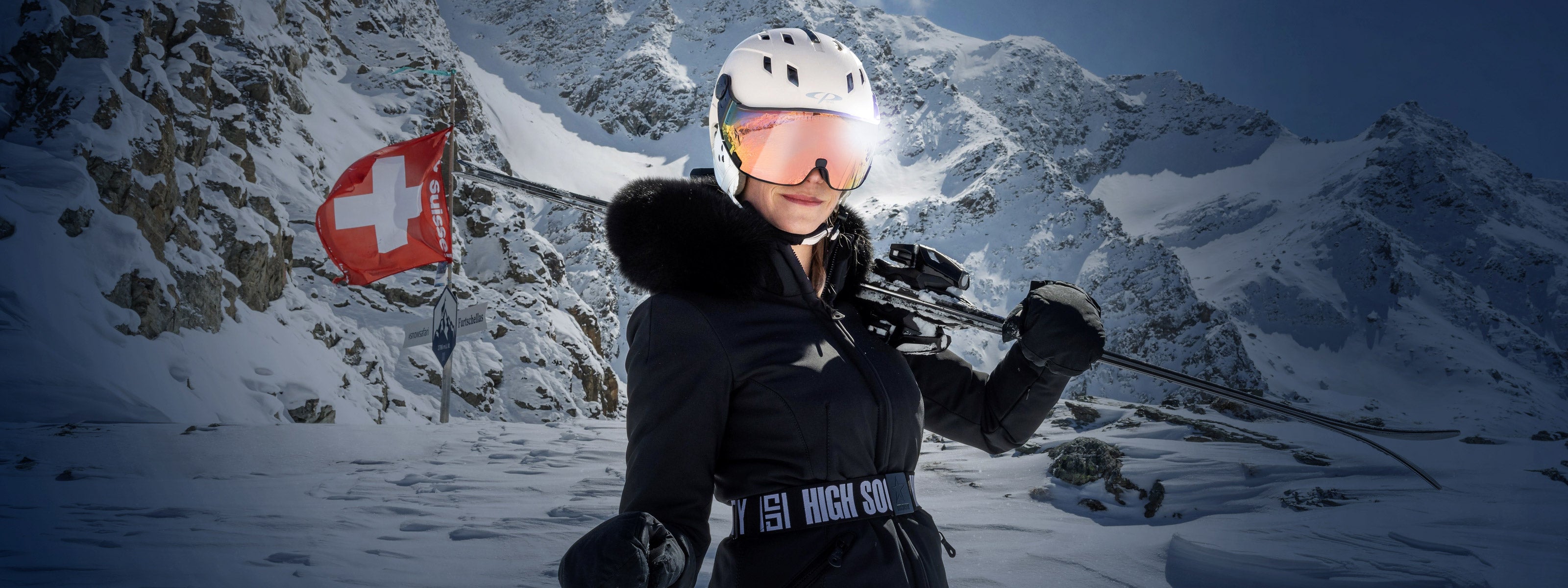 Woman wearing a CP Visor Ski Helmet in the mountains with a Swiss flag flying behind her