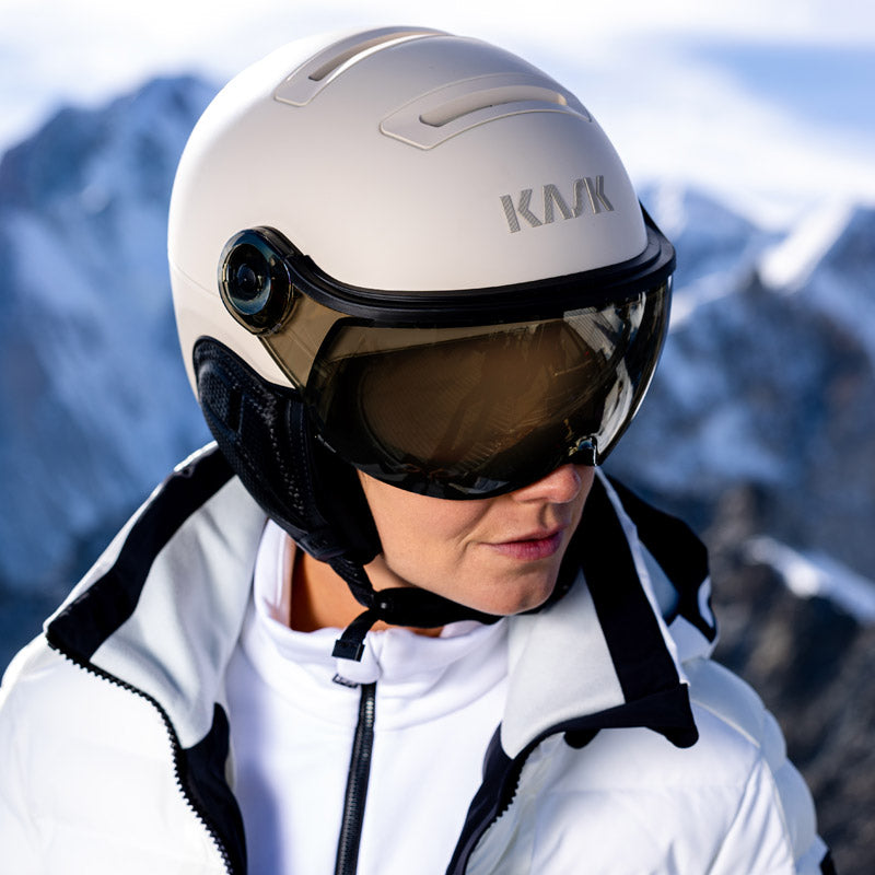 Person wearing a Kask visor ski helmet in white with a mountainous background