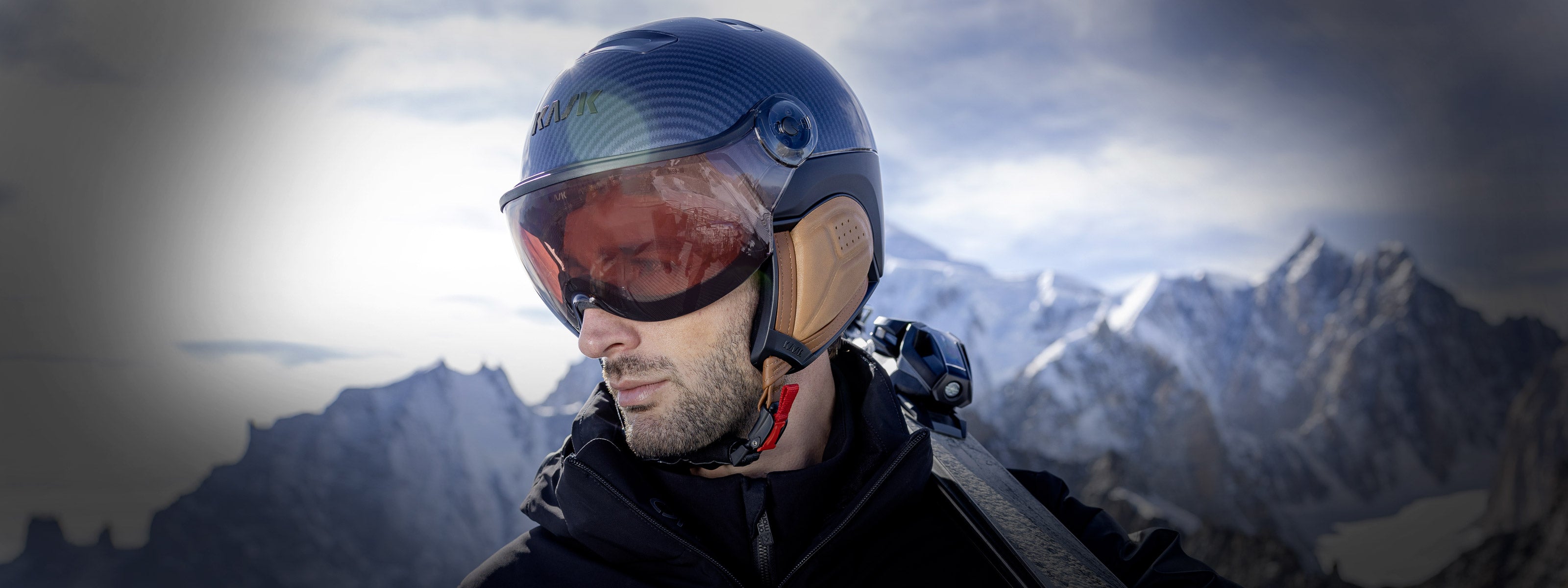 Man wearing a Kask Visor Ski Helmet carrying skis on his shoulder