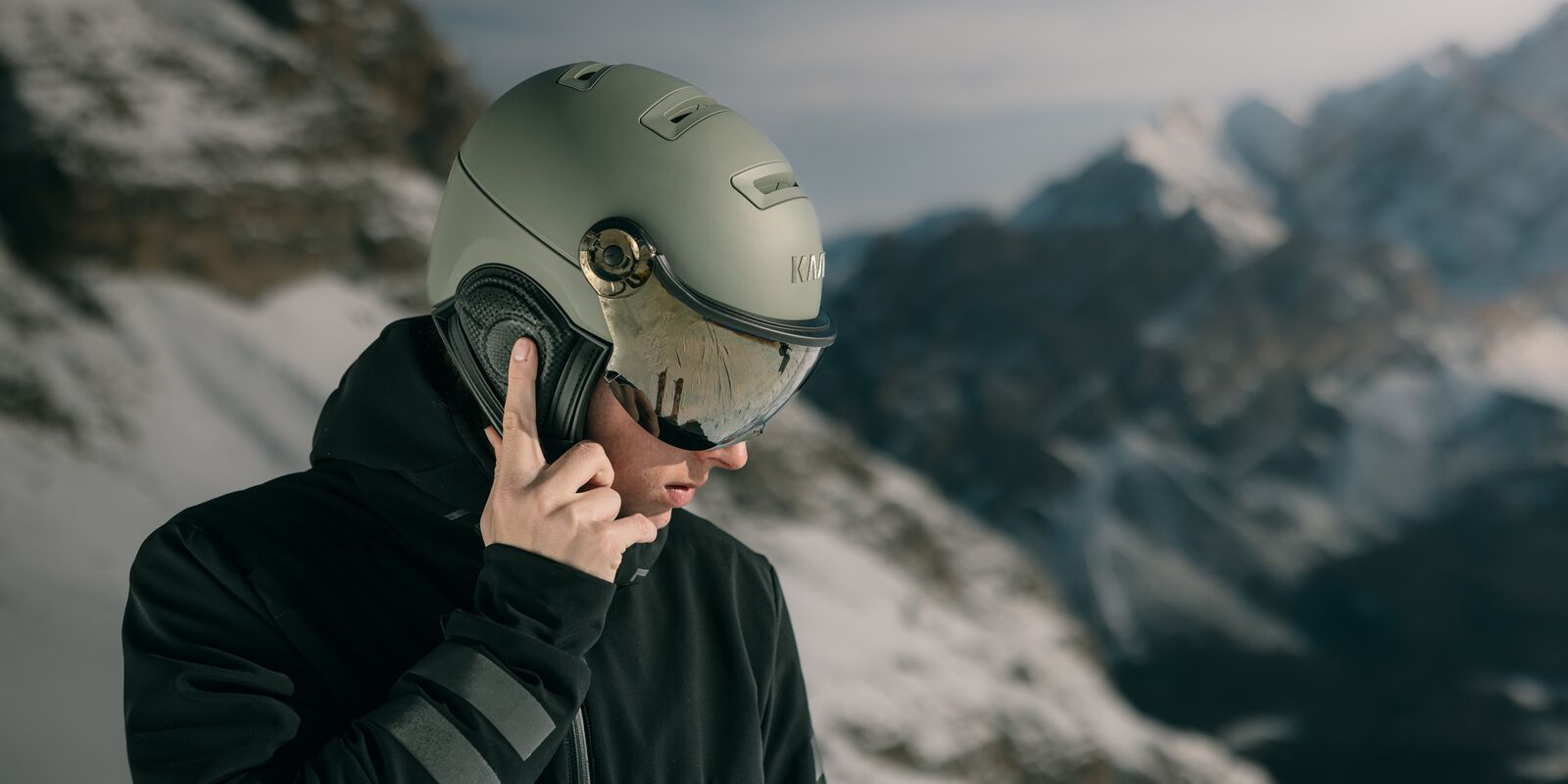 Man adjusting audio on his visor ski helmet